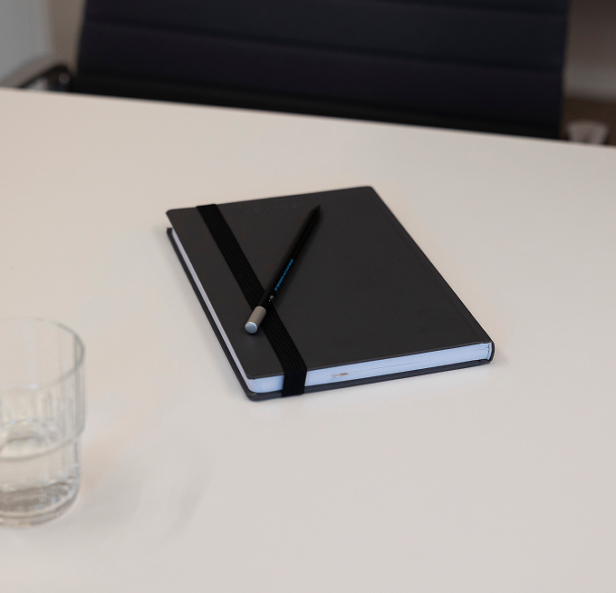 Notizbuch und Stift auf einem Besprechungstisch.